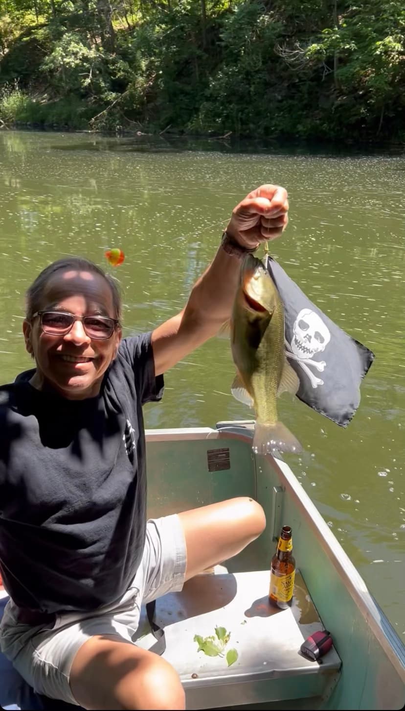 Harold smiling in a boat while holding up a fish